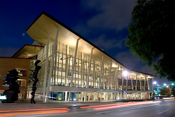View of the Hobby Center building in evening with the exterior lights illuminating the windows